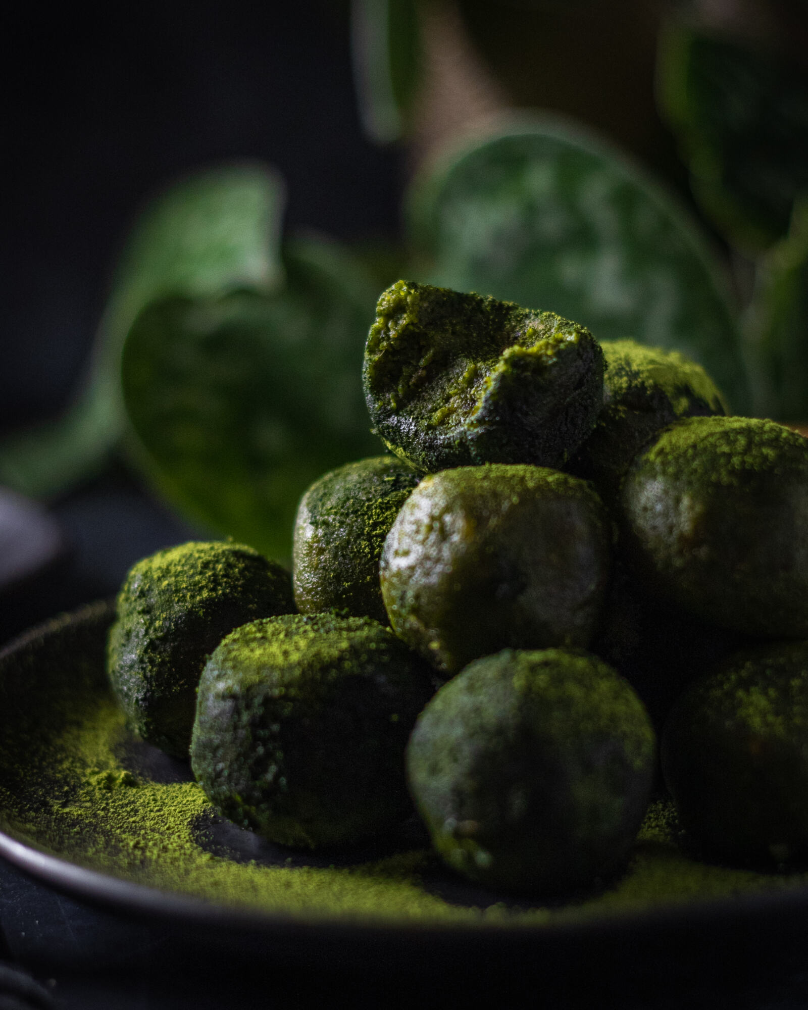 a stack of green matcha energy balls with a bite taken out of the top one