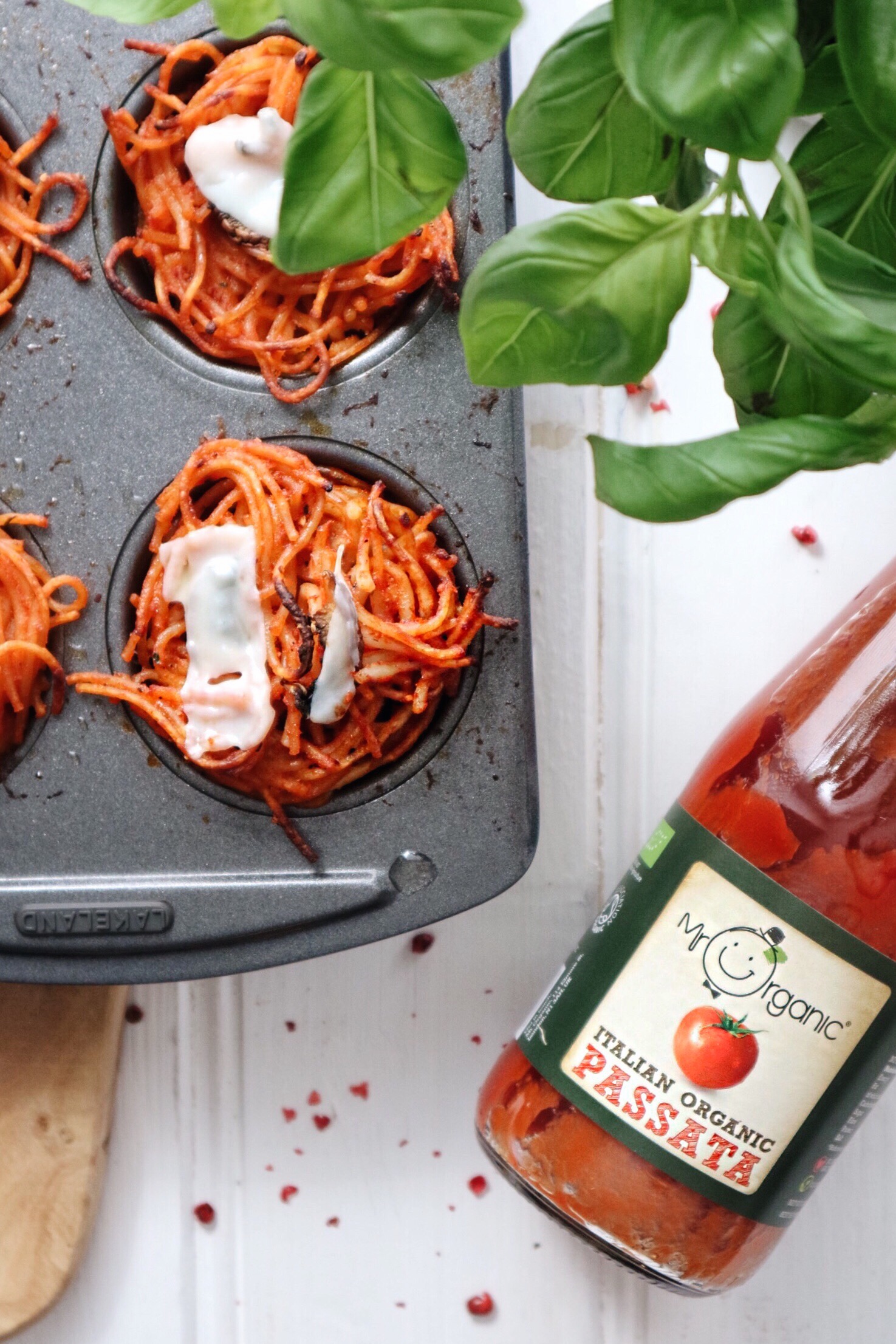 Super simple vegan recipe for pasta muffins photographed in a muffin tray alongside tomato sauce