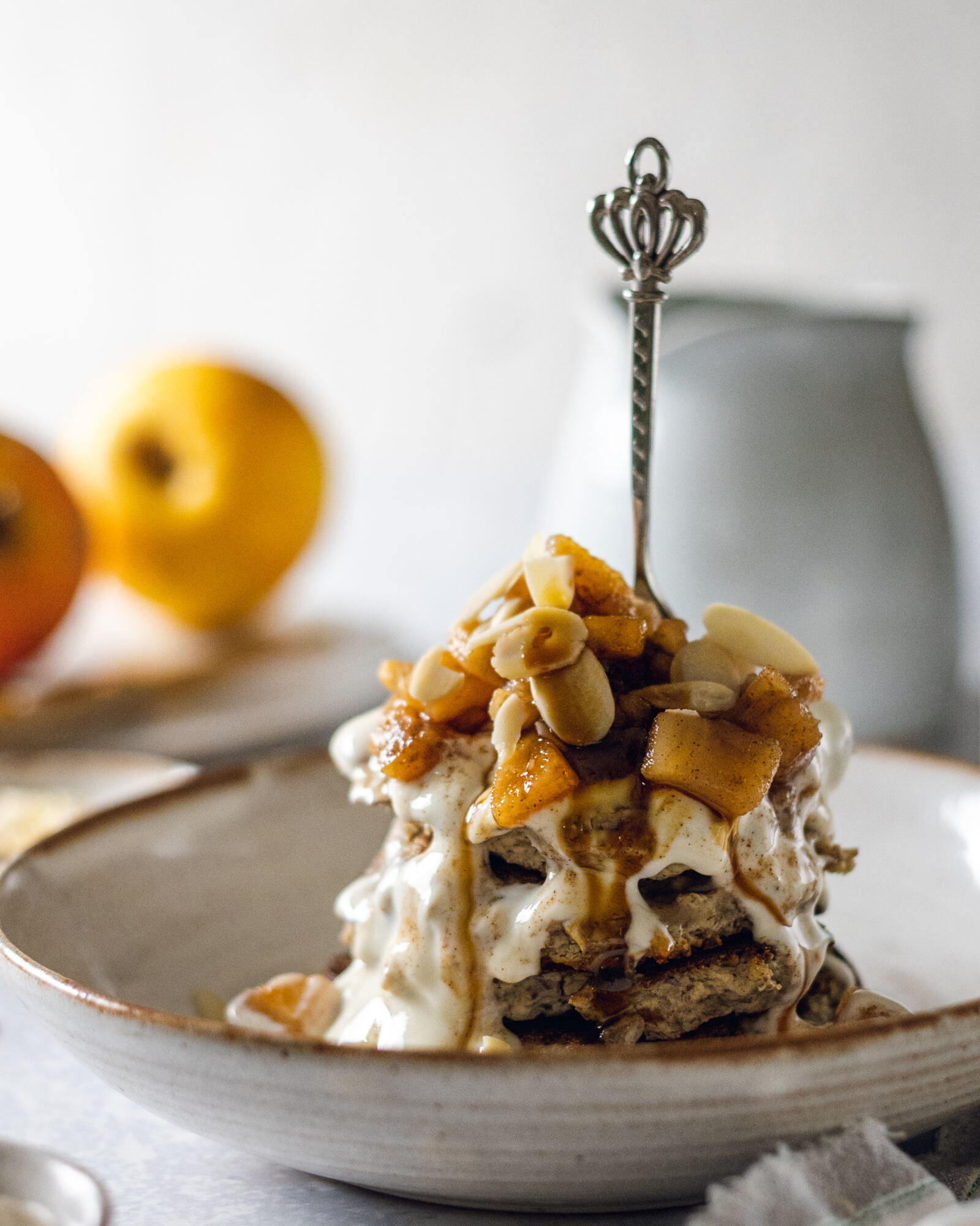 A stack of vegan protein pancakes topped with fruit and plant yogurt and with a fork in the stack.