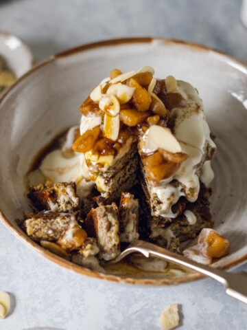 a stack of vegan protein pancakes in a bowl, topped with vegan yogurt and fruit