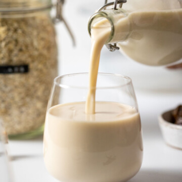 easy homemade oat milk gluten free poured from a glass bottle into a glass