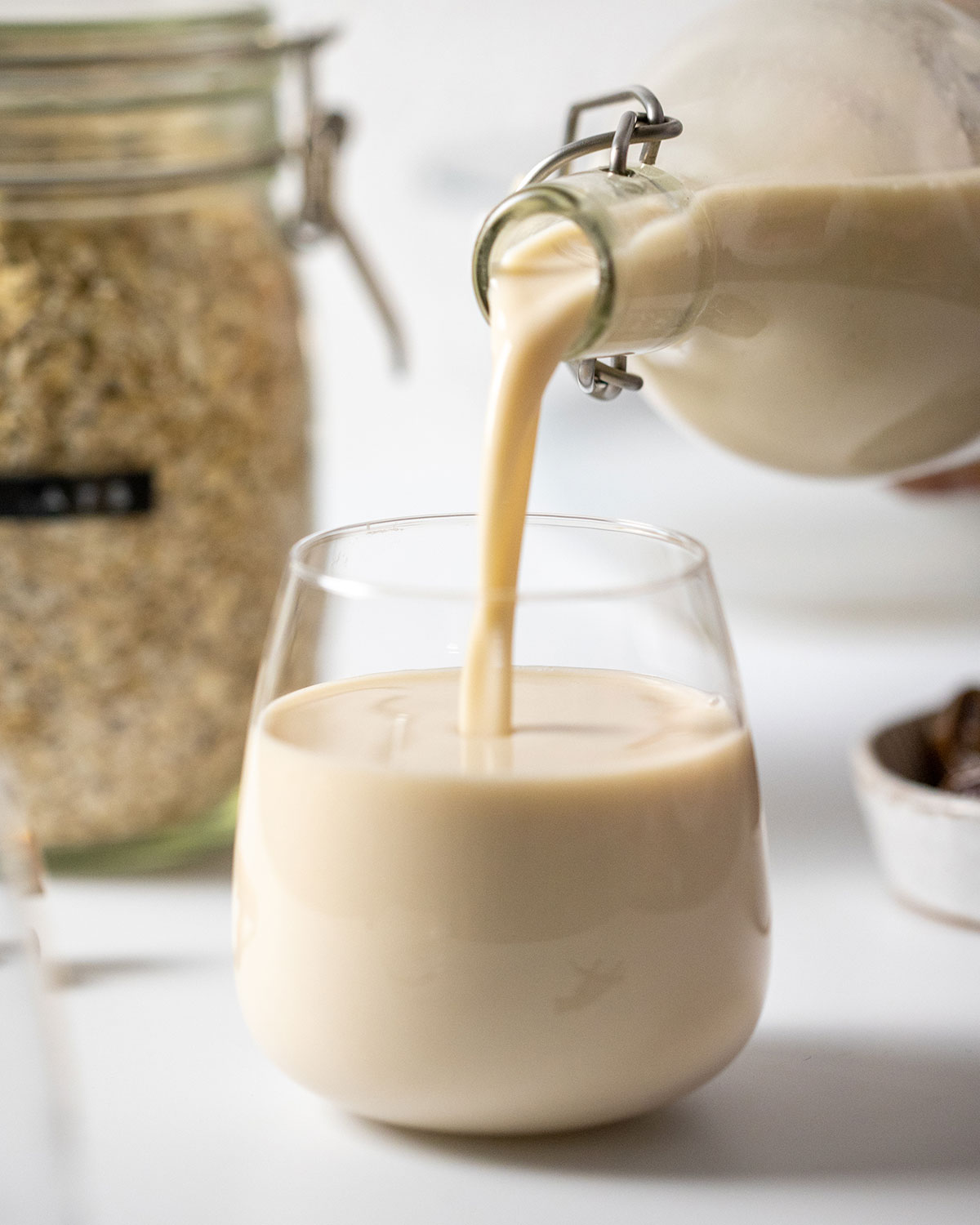 easy homemade oat milk gluten free poured from a glass bottle into a glass