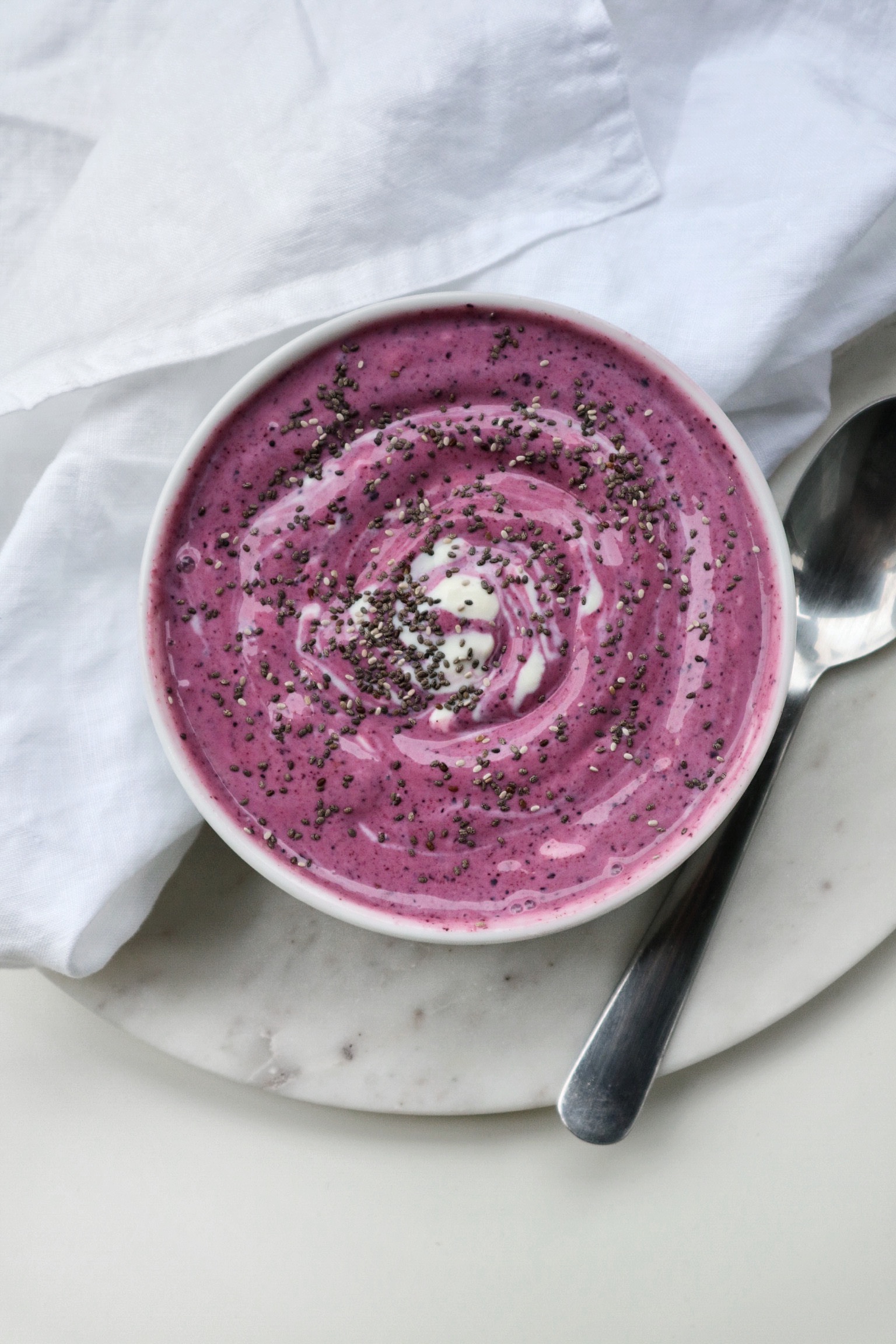 a pink vegan keto breakfast bowl topped with chia seeds and coconut yogurt on a white background