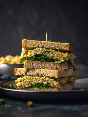 2 chickpea tuna sandwiches on top of each other on a black plate