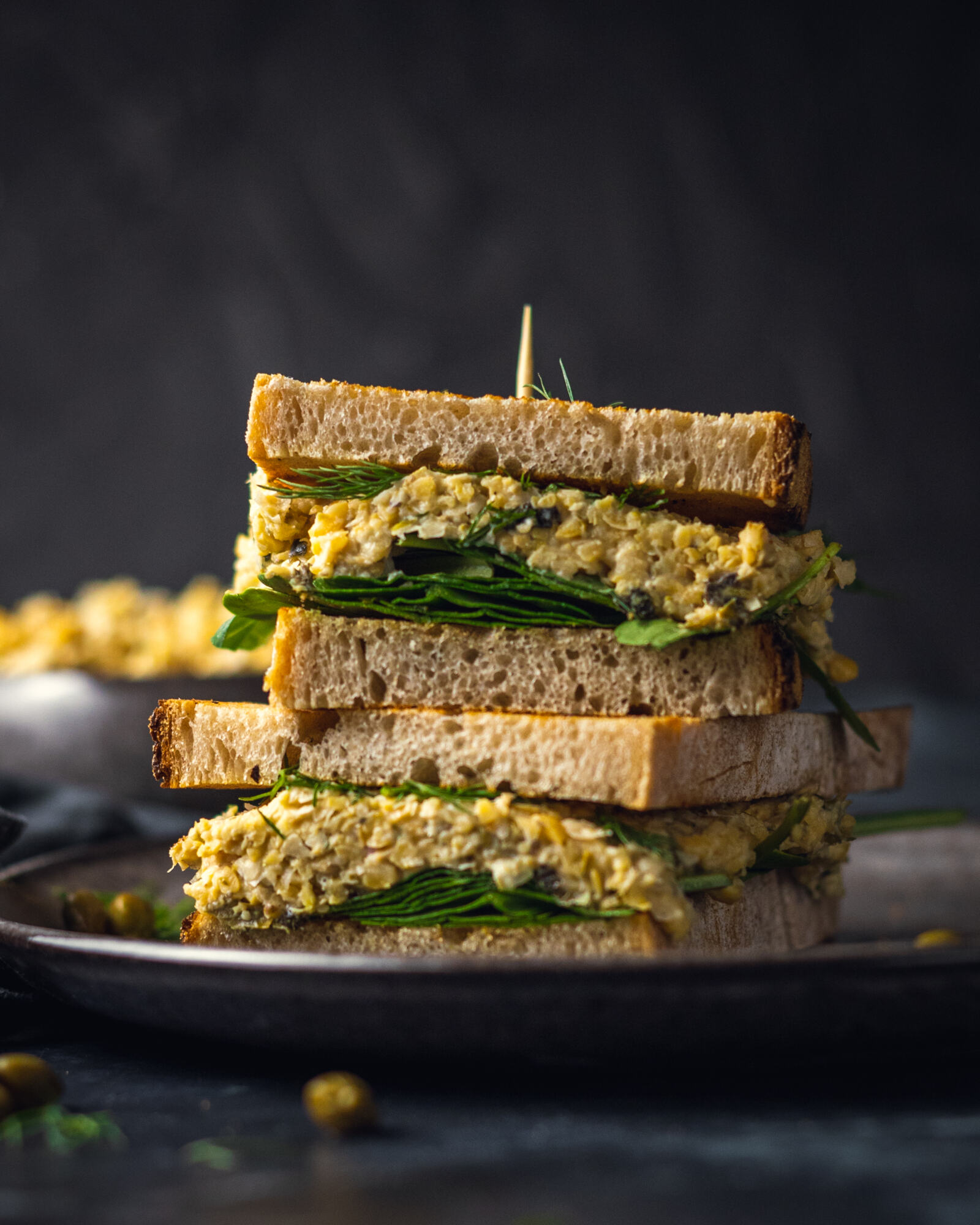 2 chickpea tuna sandwiches on top of each other on a black plate