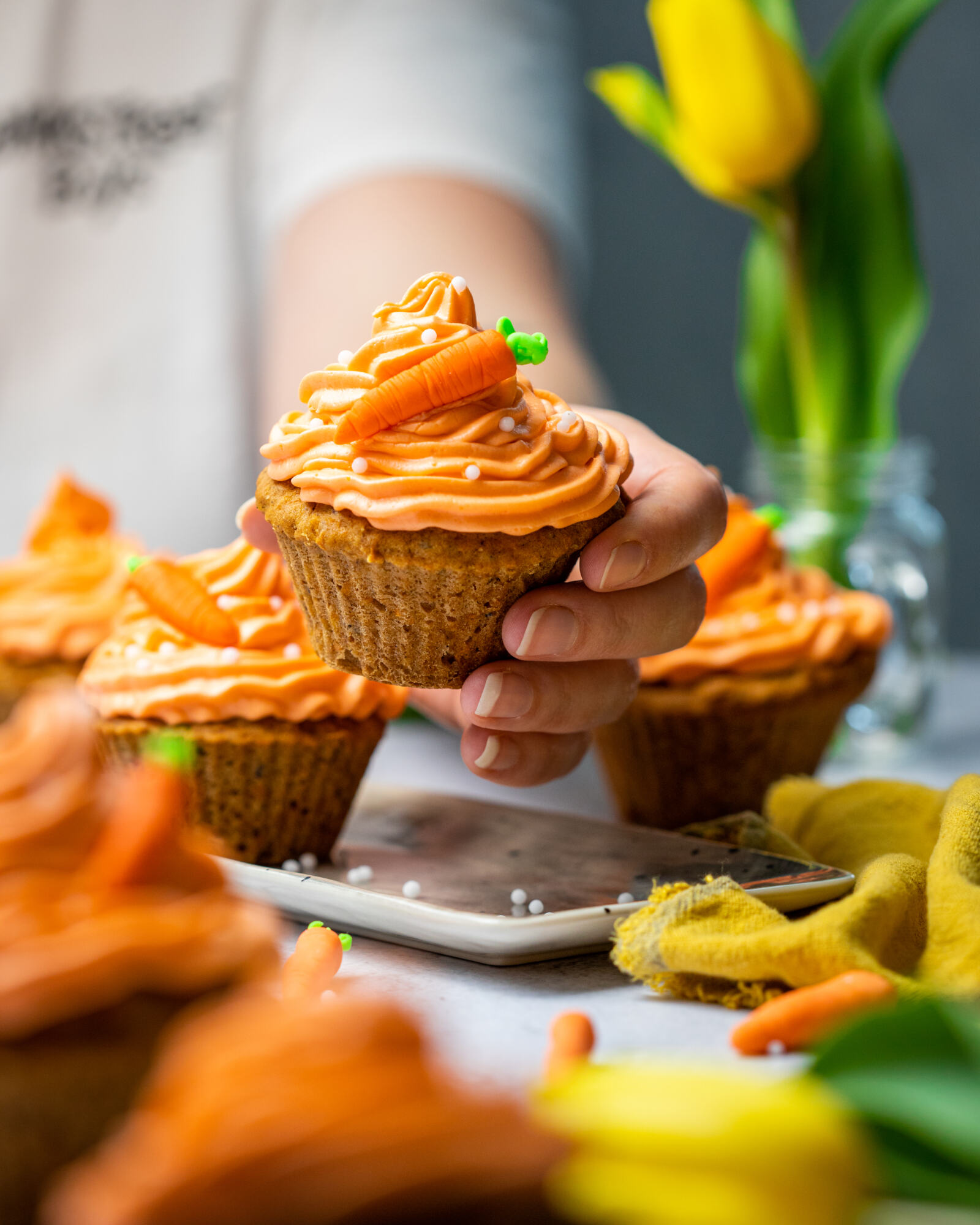 A hand holding a carrot cake muffin into the camera