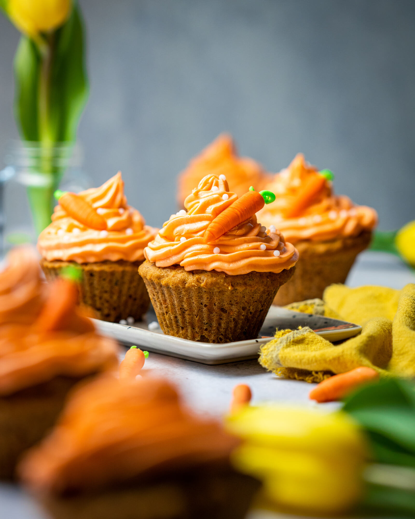 Vegan carrot cake muffins on a white marble table with flowers in the background