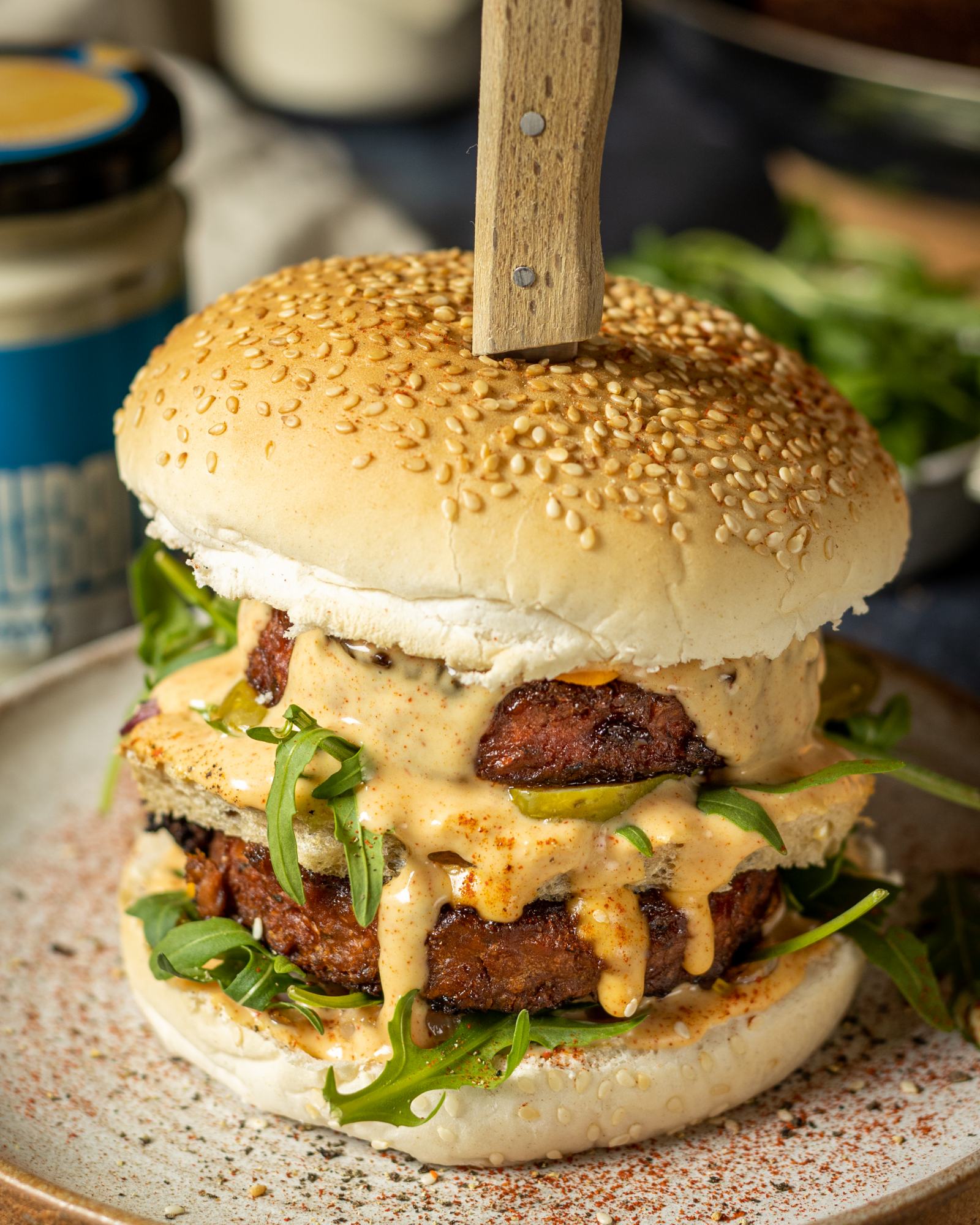 Vegan Mcdonalds Burger by a vegan big mac recipe in a seeded burger bun and 2 vegan burger patties on a white plate