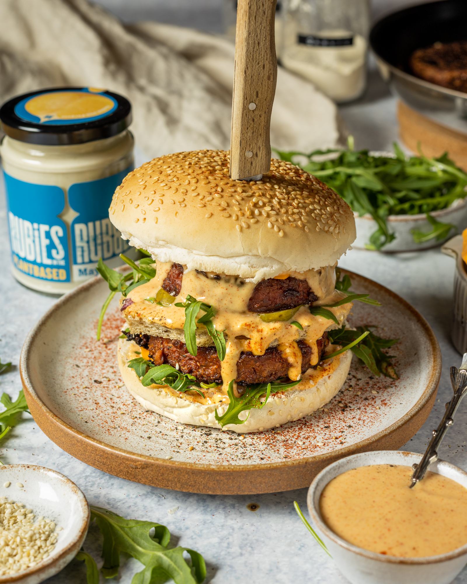 Vegan Mcdonalds Burger by a vegan big mac recipe in a seeded burger bun and 2 vegan burger patties on a white plate