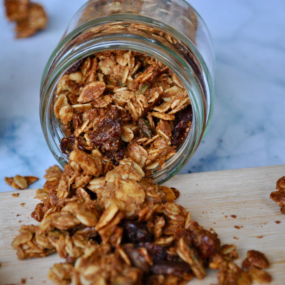 A close-up photograph of homemade granola with cinnamon and cardamom