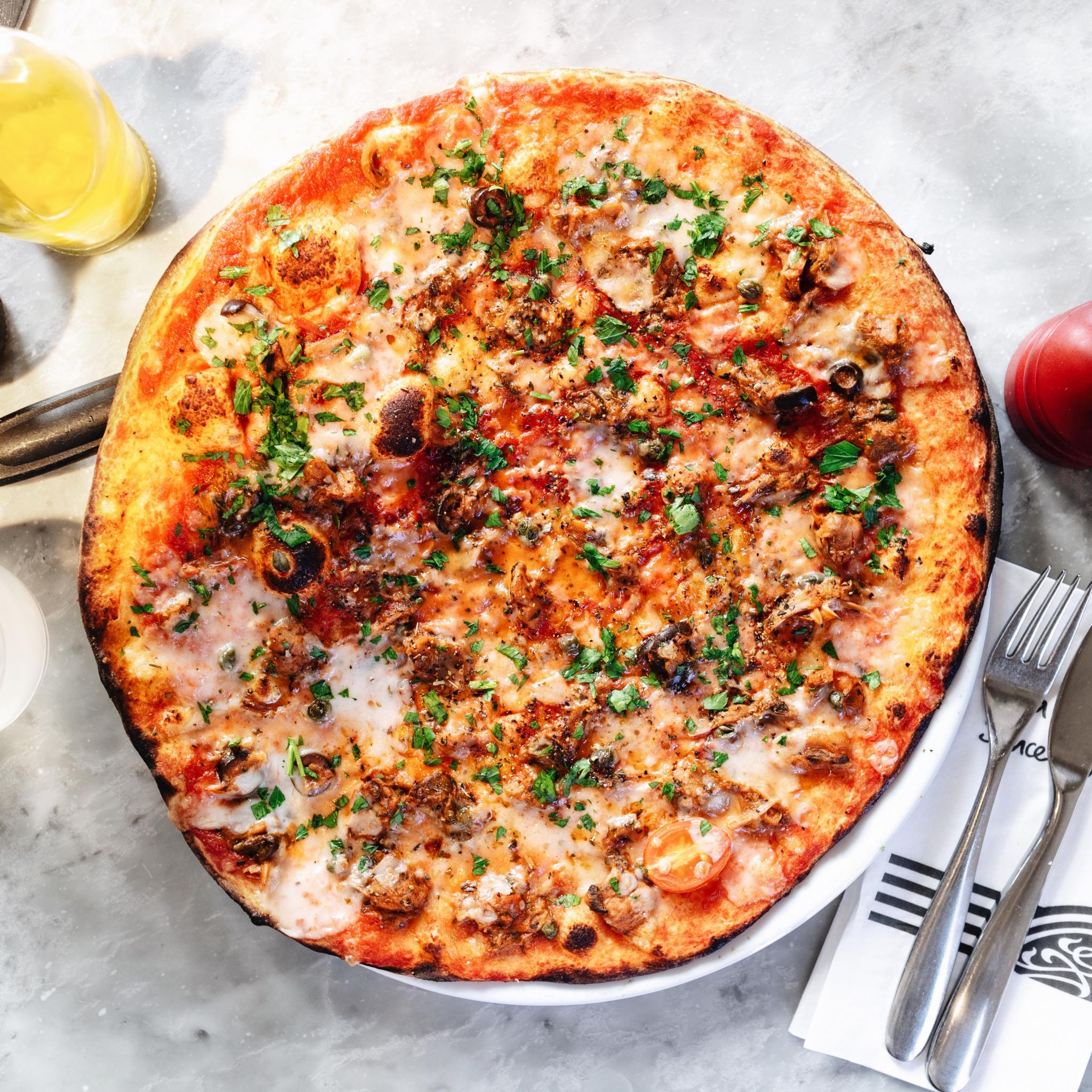 whole vegan pizza on a marble table at pizza express