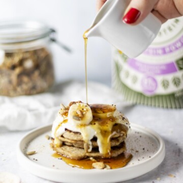 Vegan and gluten free Rice Protein Pancakes on a white plate being drizzled with syrup