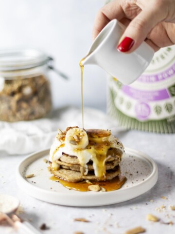 Vegan and gluten free Rice Protein Pancakes on a white plate being drizzled with syrup