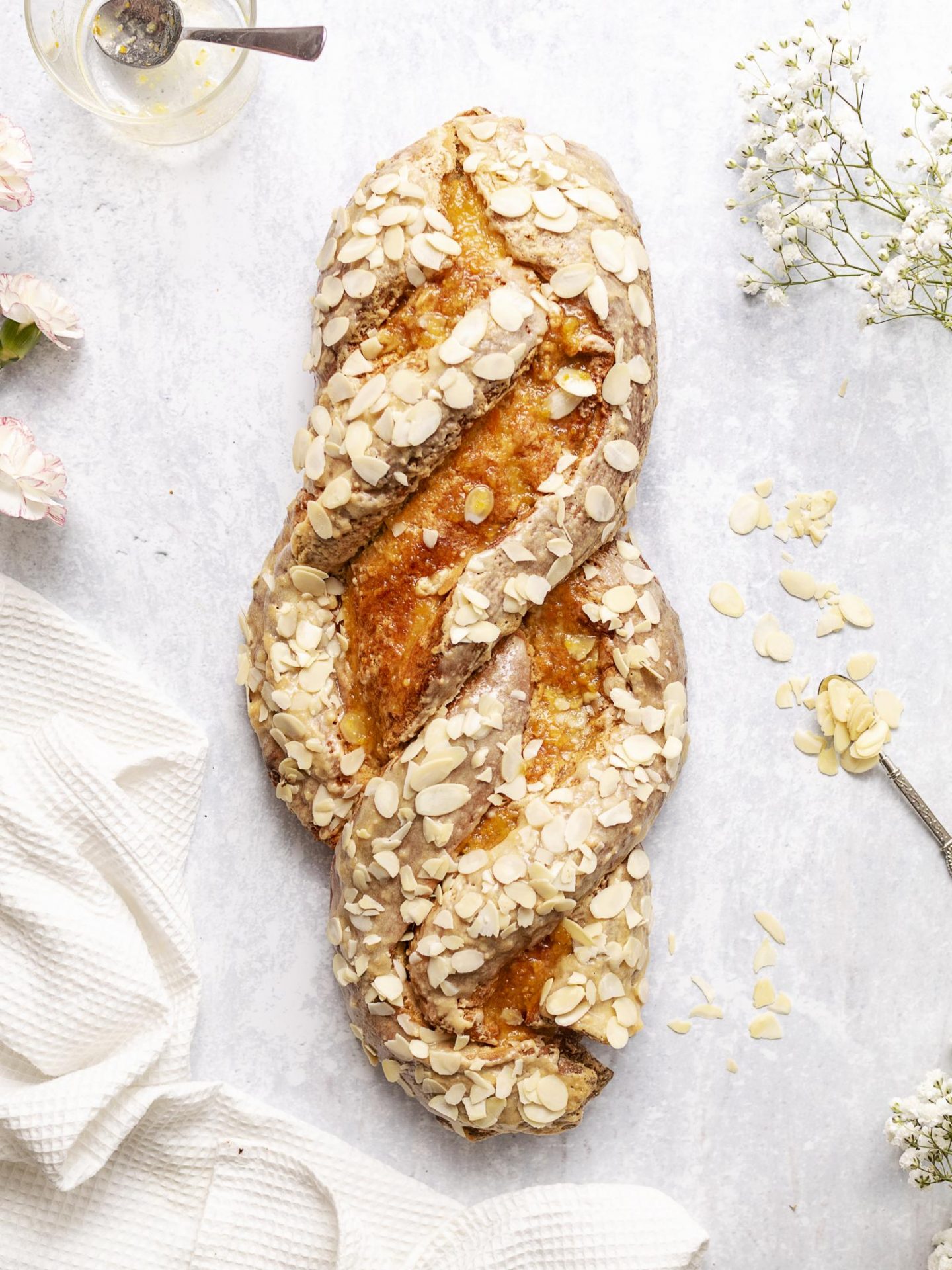 Vegan Easter Plait with marzipan and almonds on a white marble backdrop