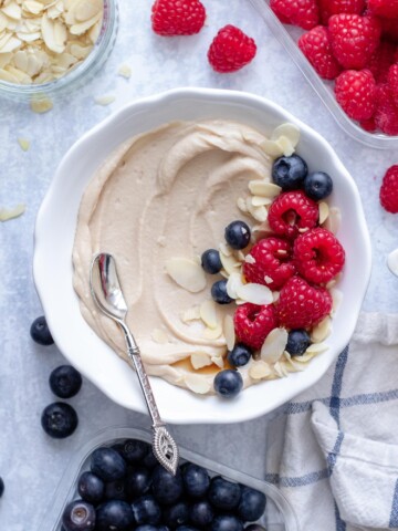 Vegan Protein Cheesecake Pudding in a white bowl with fruit on top