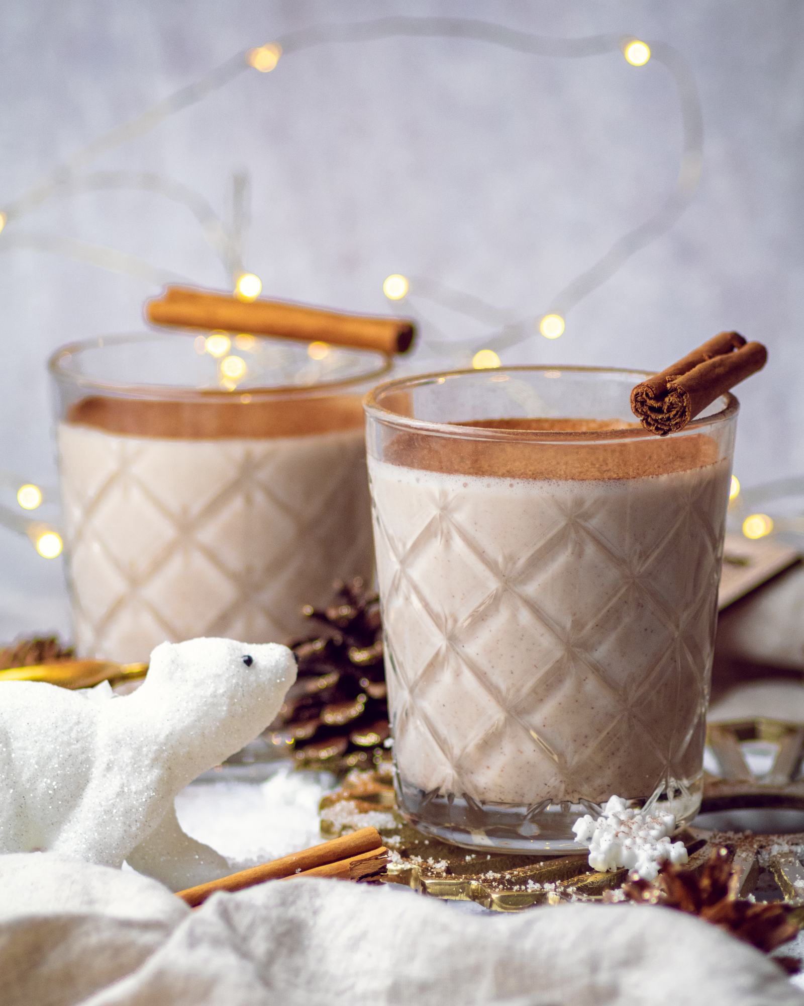 a small white bear decoration next to a glassful of Vegan Oat Milk Eggnog