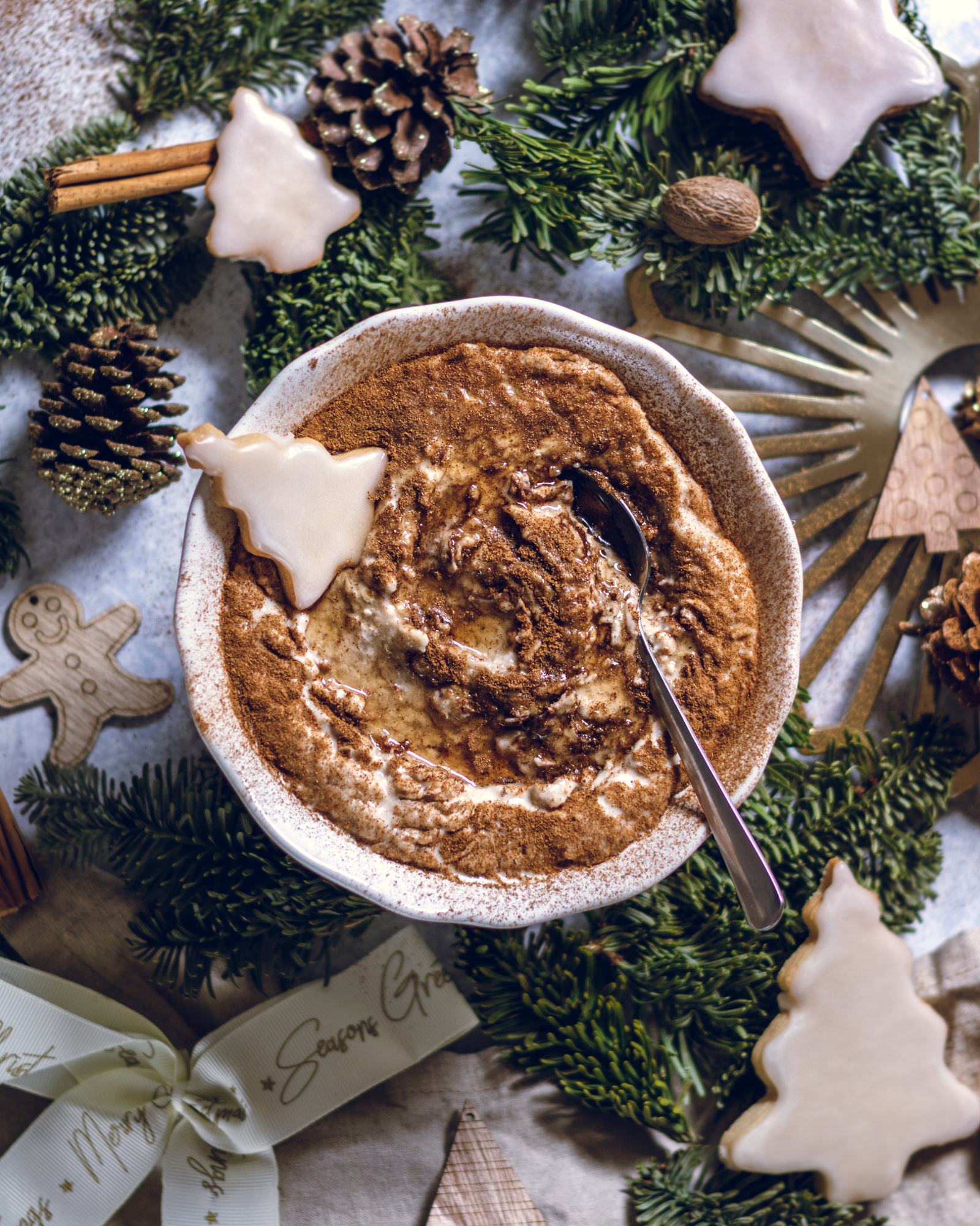 Creamy Vegan Eggnog Porridge in a white bowl topped with a christmas tree cookie