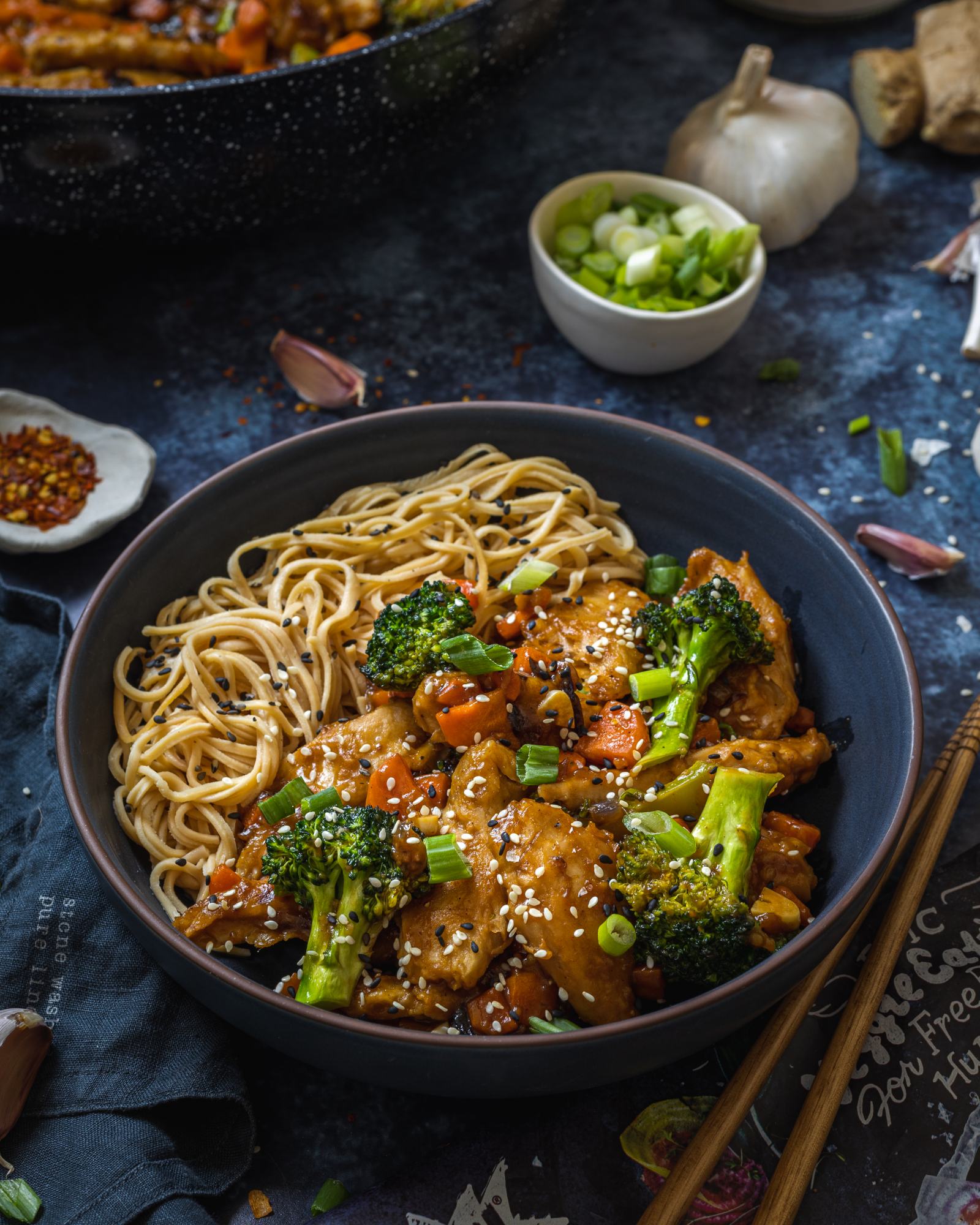 a dinner bowl on the table filled with noodles, vegetables and vegan teriyaki sauce