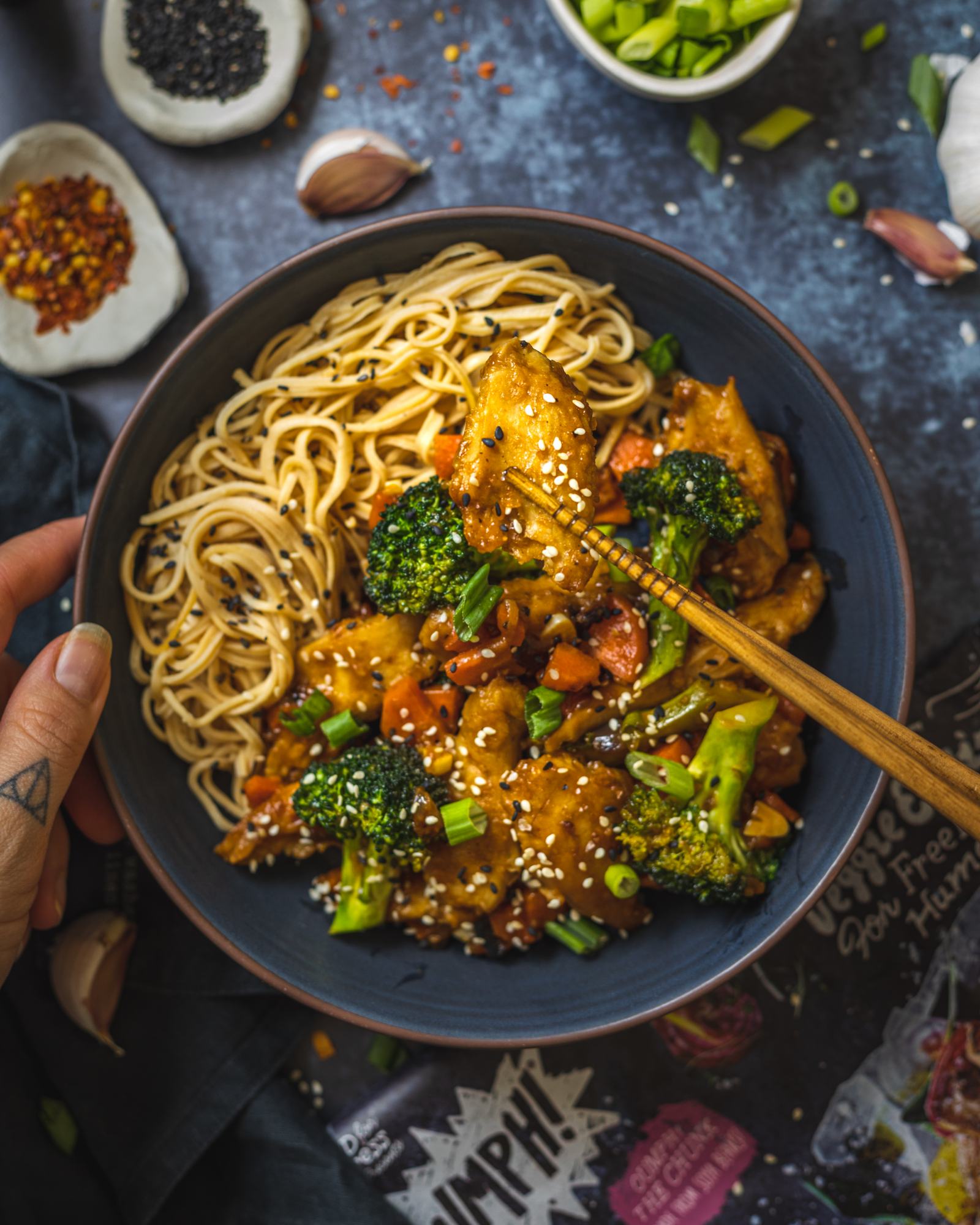 2 chopsticks holding a vegan chicken piece coated in vegan teriyaki sauce into the camera