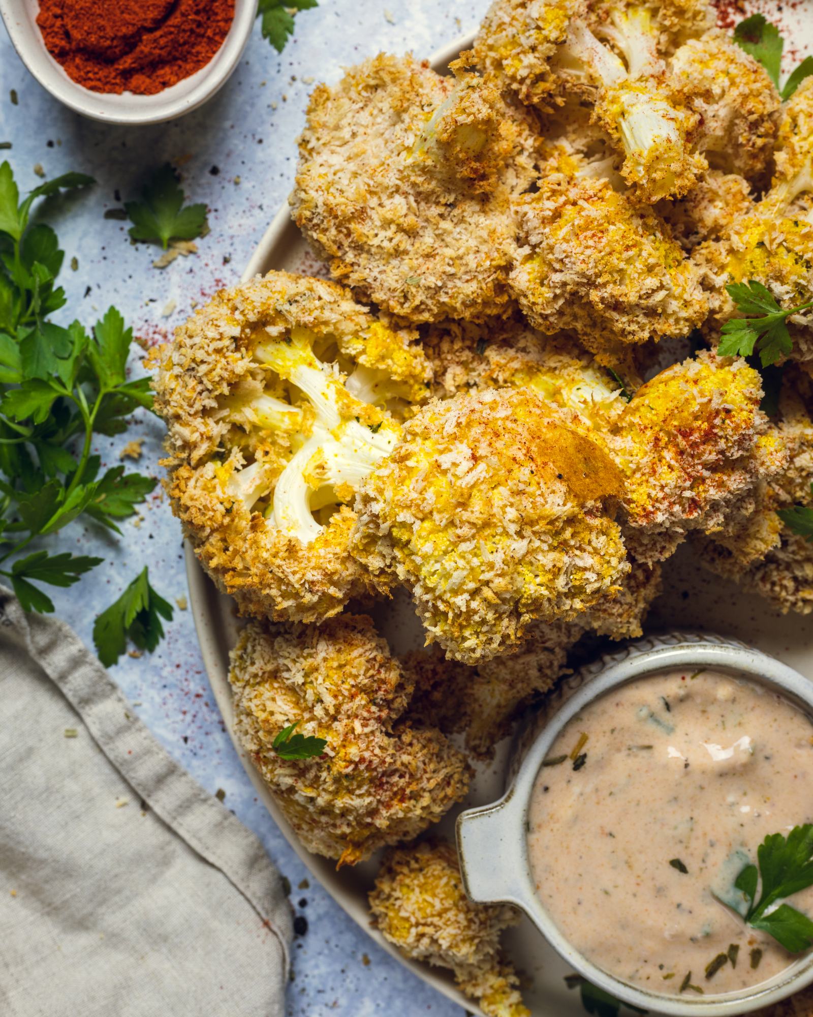 Air fried vegan cauliflower wings are shown up close on a serving platter with a dip on the side.