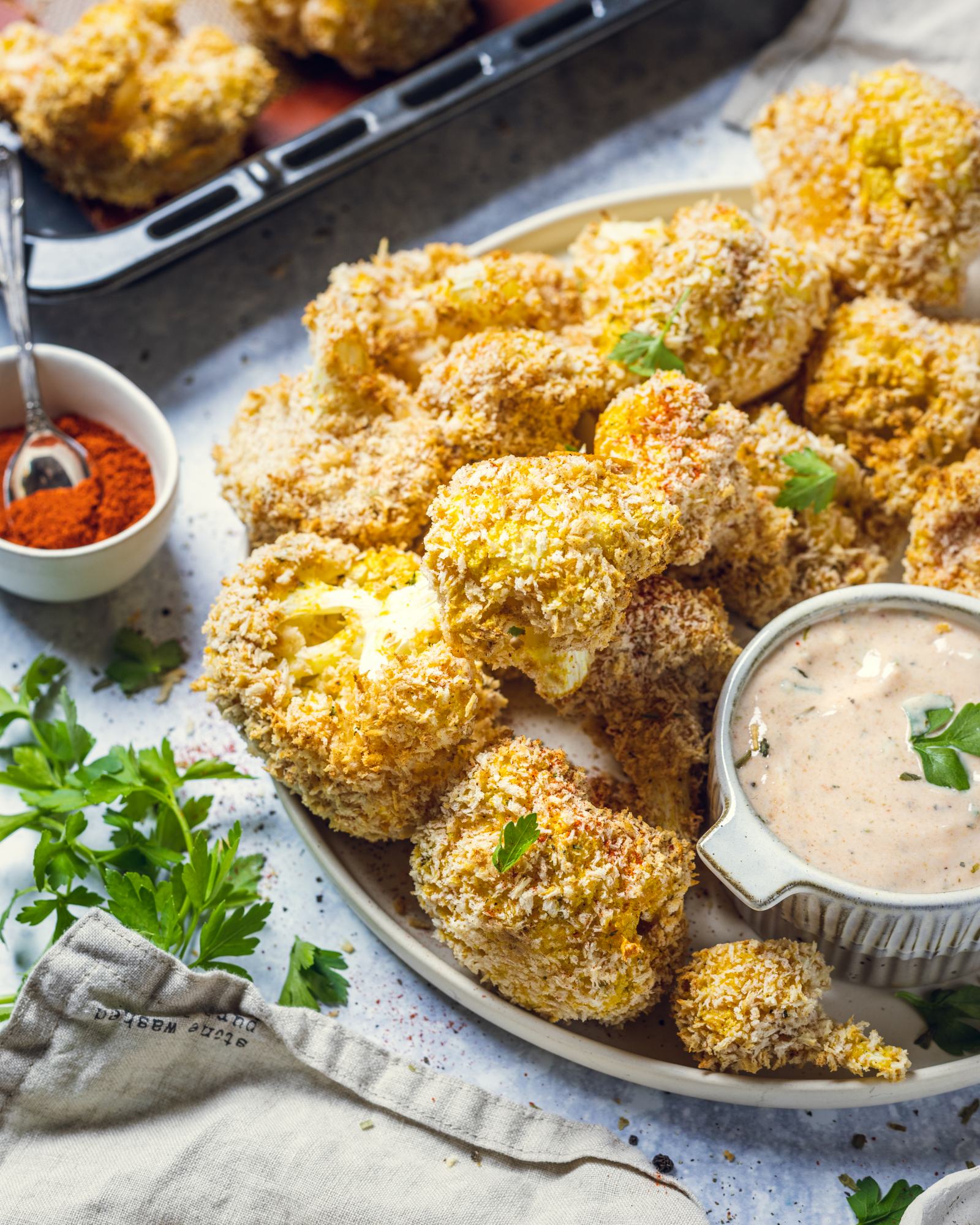 Air fried vegan cauliflower wings can be seen on a round serving platter with a vegan yogurt dip on the side.