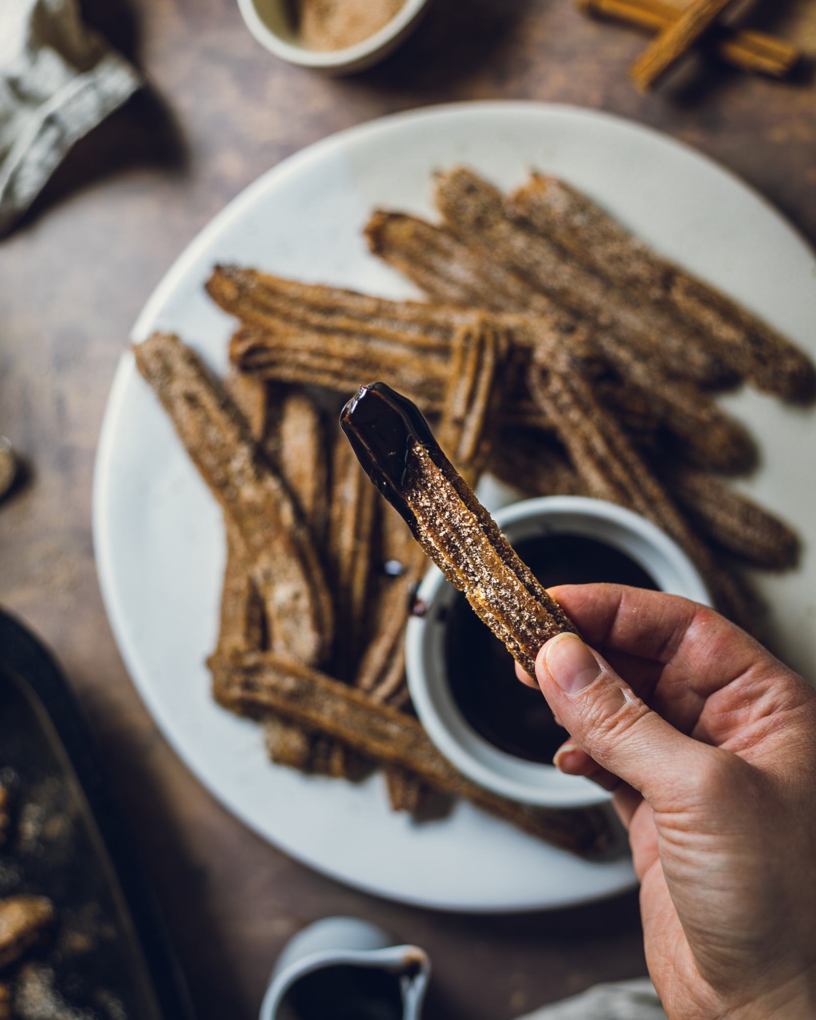 hand holding a Churro with chocolate sauce