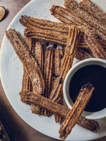 Baked Vegan Churros on a plate with vegan chocolate dip