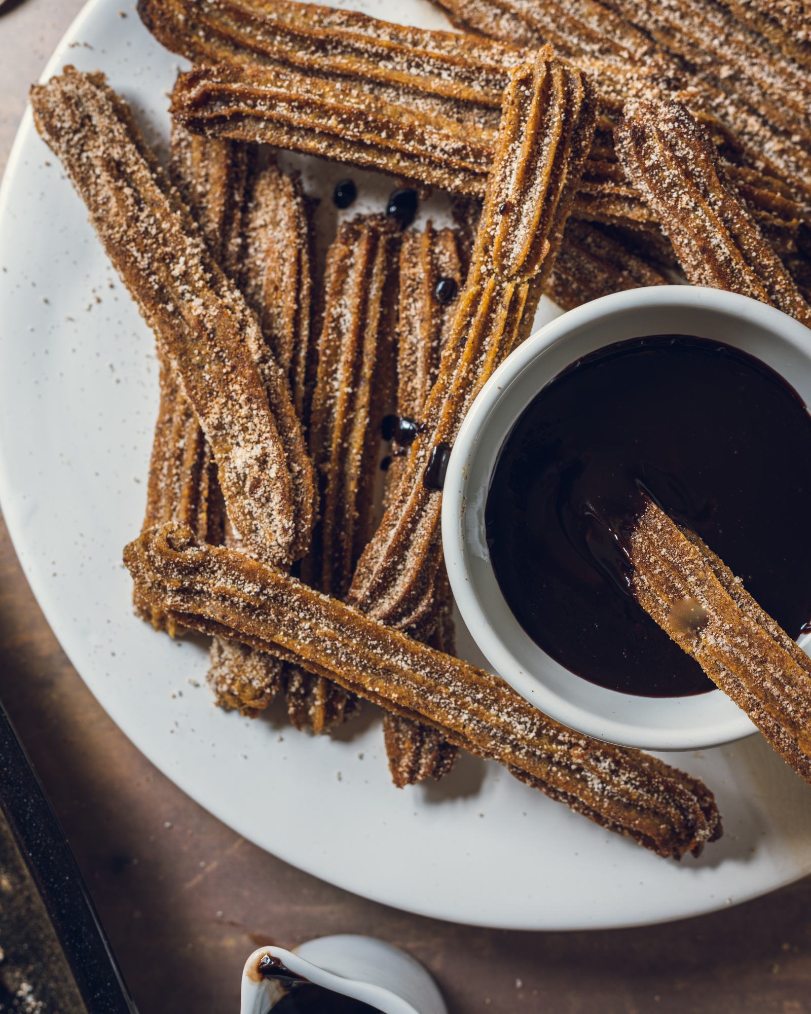 Baked Vegan Churros on a white plate with vegan chocolate dip