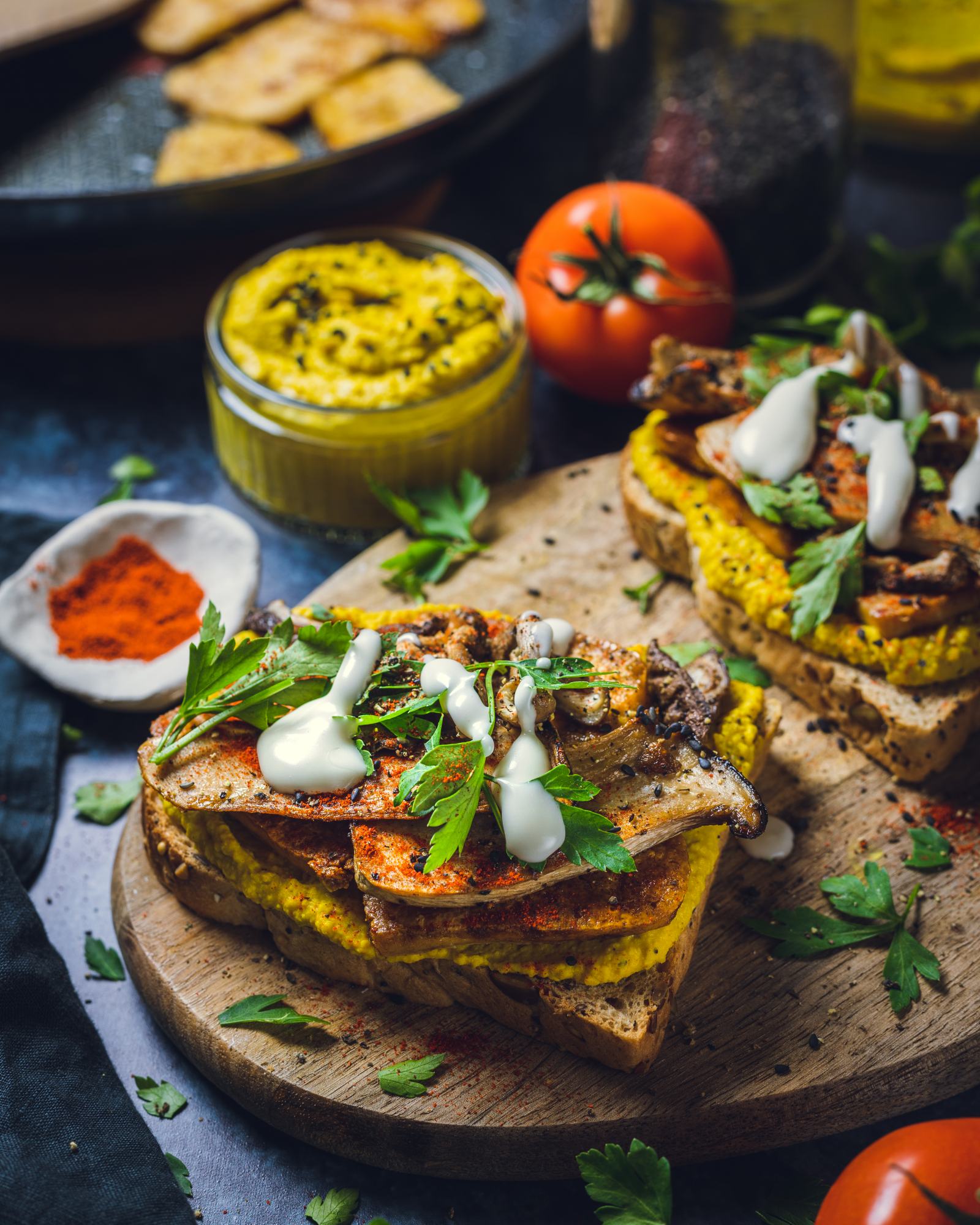Slices of curried hummus sandwiches with tofu and mushrooms on a wooden board.
