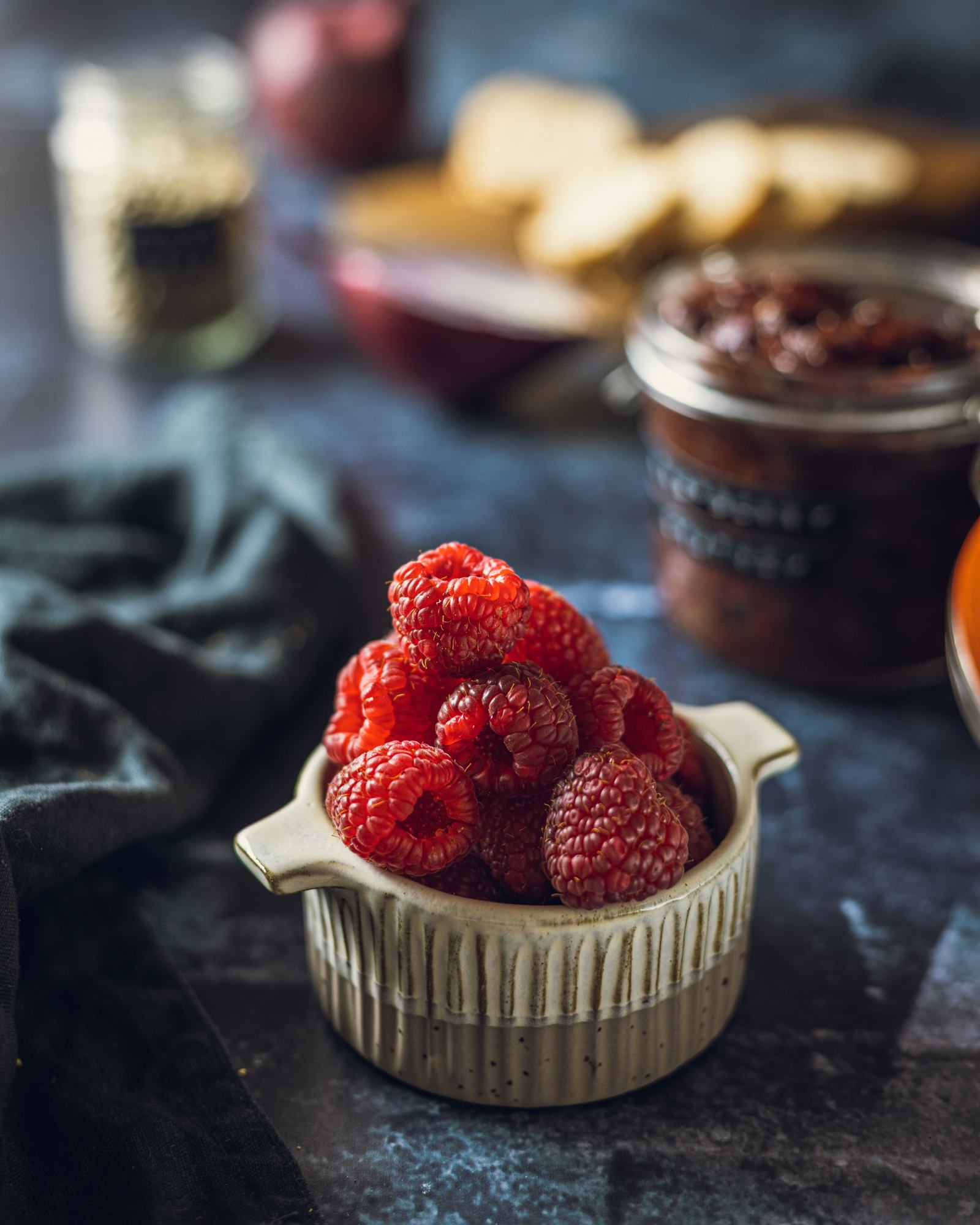 A small bowl filled with fresh raspberries with the chutney in the background.