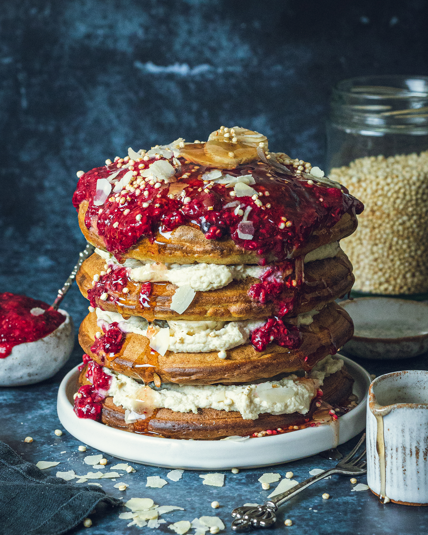 a stack of 4 fluffy vegan pancakes with vegan protein yogurt in between the layers and a generous serving of homemade chia jam on top.