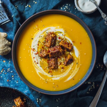 vegan swede soup and a blue bowl topped with vegan cream and Tempeh