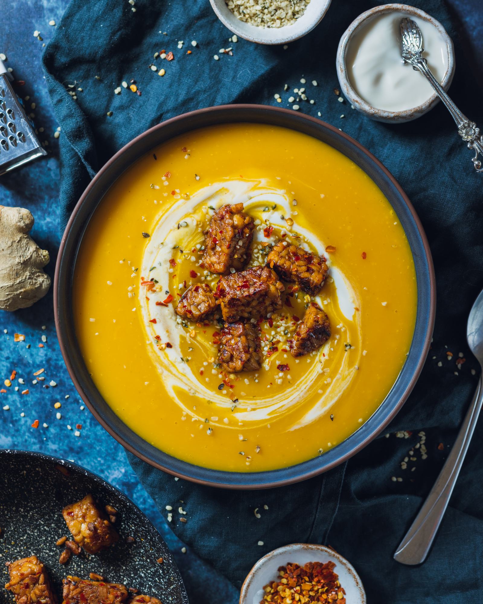 vegan swede soup and a blue bowl topped with vegan cream and Tempeh