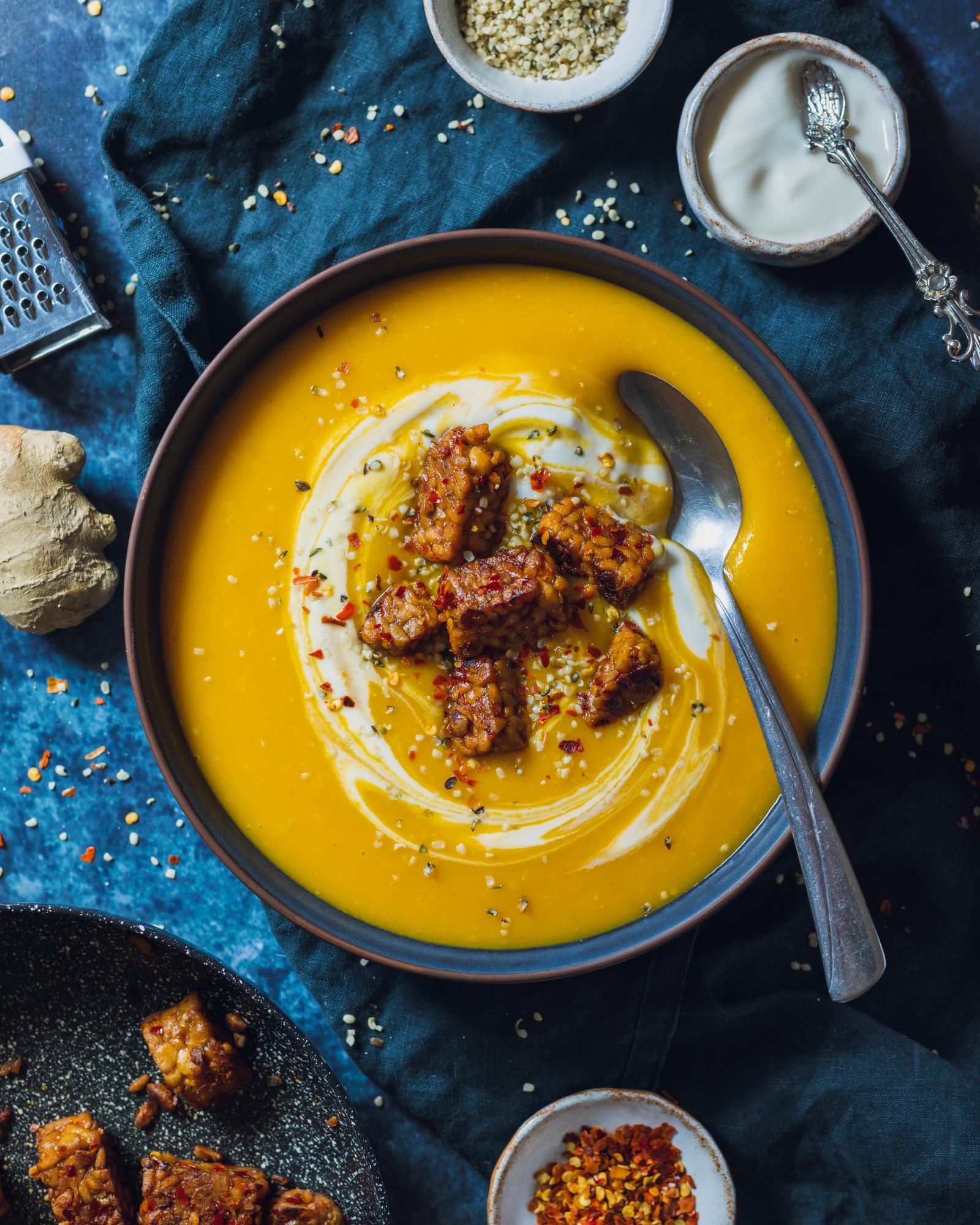 A warming bowl is filled with vibrant swede soup and topped with tempeh.