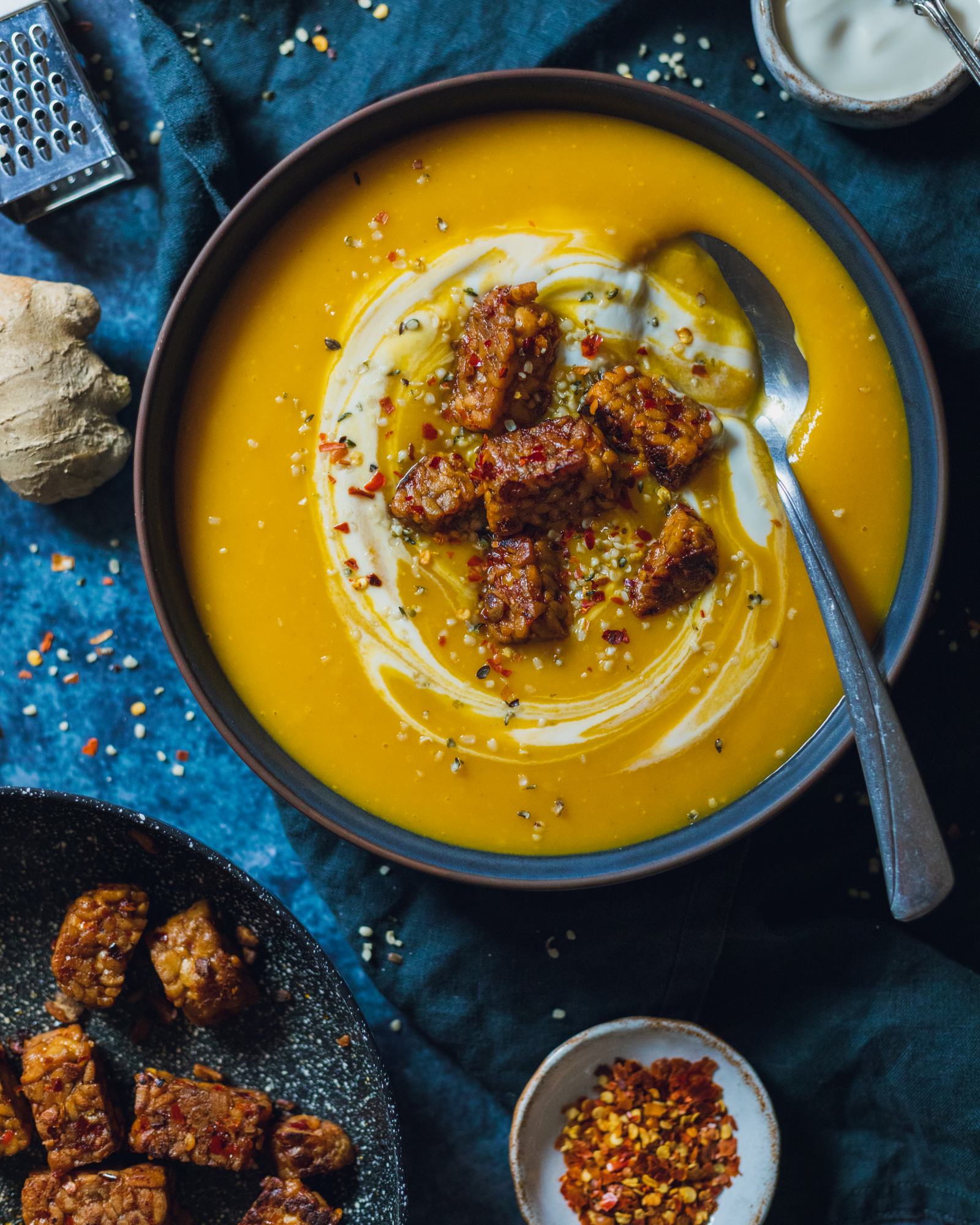 Spicy Swede Soup in a bowl topped with tempeh and a spoon in the bowl