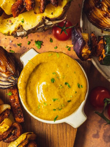 Pineapple Curry BBQ Sauce in a small bowl next to grilled skewers