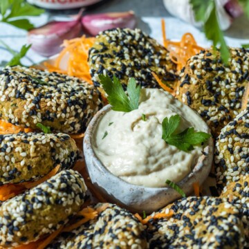 crispy baked falafels on a serving platter with a tahini dip in the middle