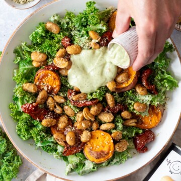 a bowl filled with kale caesar salad and a creamy avocado caesar dressing