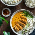 vegan tempeh katsu curry in a bowl with rice on a dark wooden table