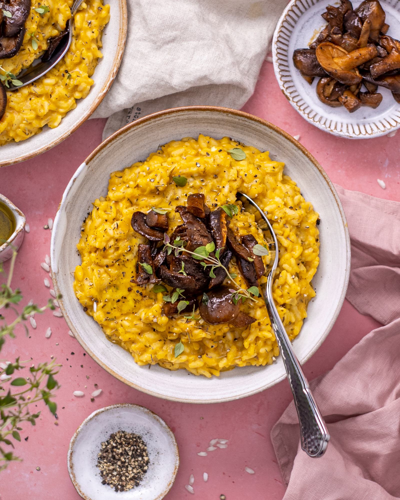 a bowl of vibrant pumpkin risotto on a pink table top