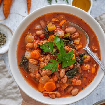 Kale and Borlotti Bean Soup in a bowl with a spoon