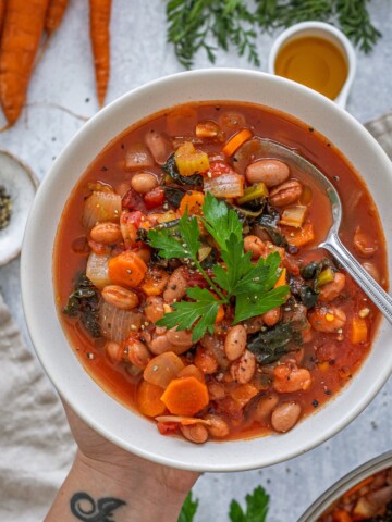 Kale and Borlotti Bean Soup in a bowl with a spoon