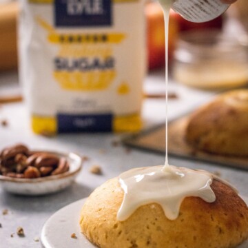 Vegan Apple Cinnamon Bun - photographed from the front with a drizzle of frosting being poured on top