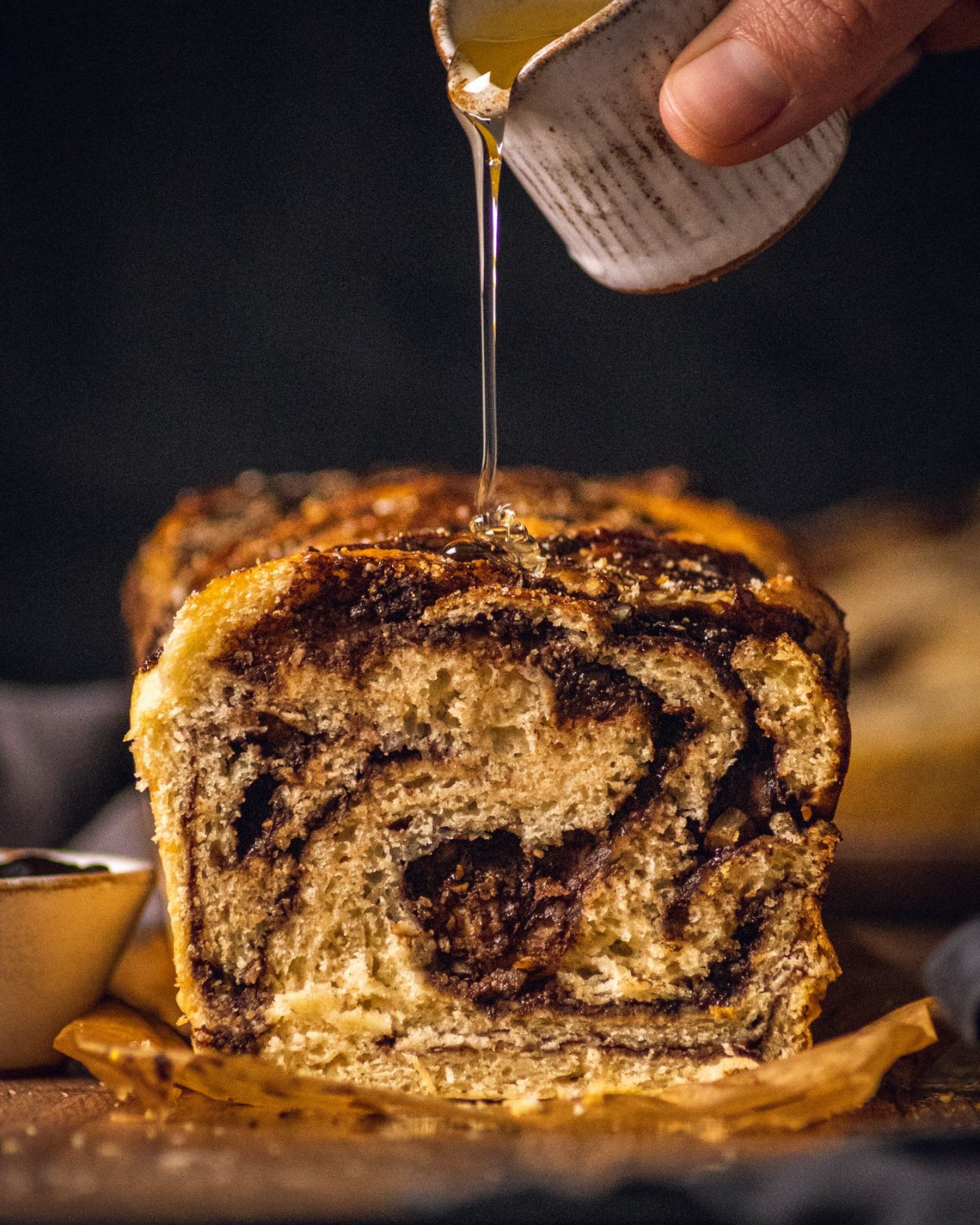 syrup being poured on a chocolate and hazelnut babka