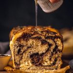 syrup being poured onto a vegan chocolate and hazelnut babka