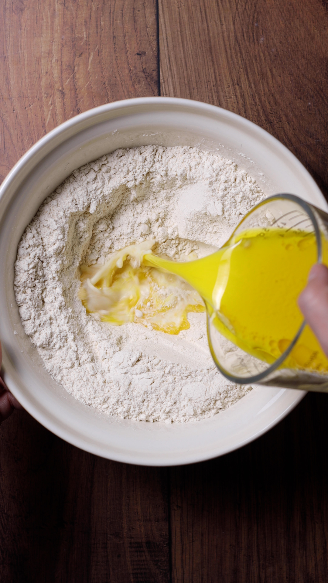 Liquid ingredients added to a bowl of dry ingredients.