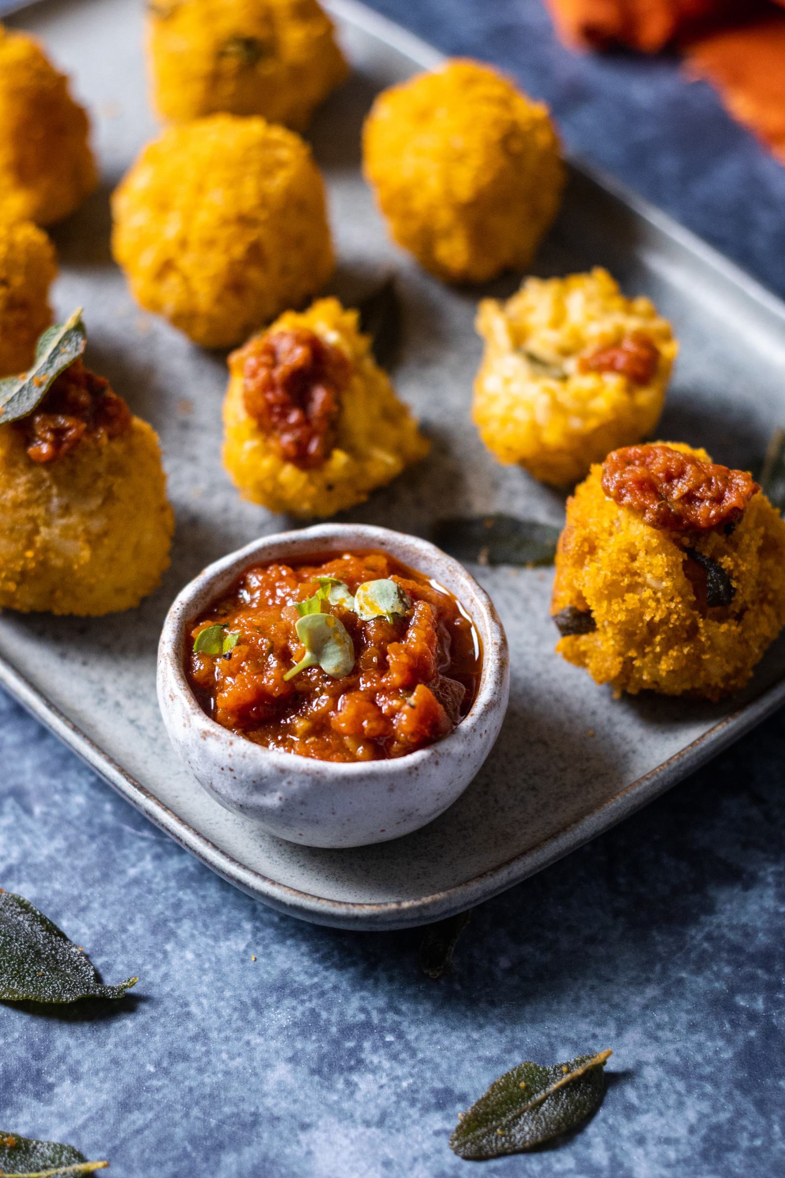 a tomato dip on the edge of a serving platter with vegan arancini