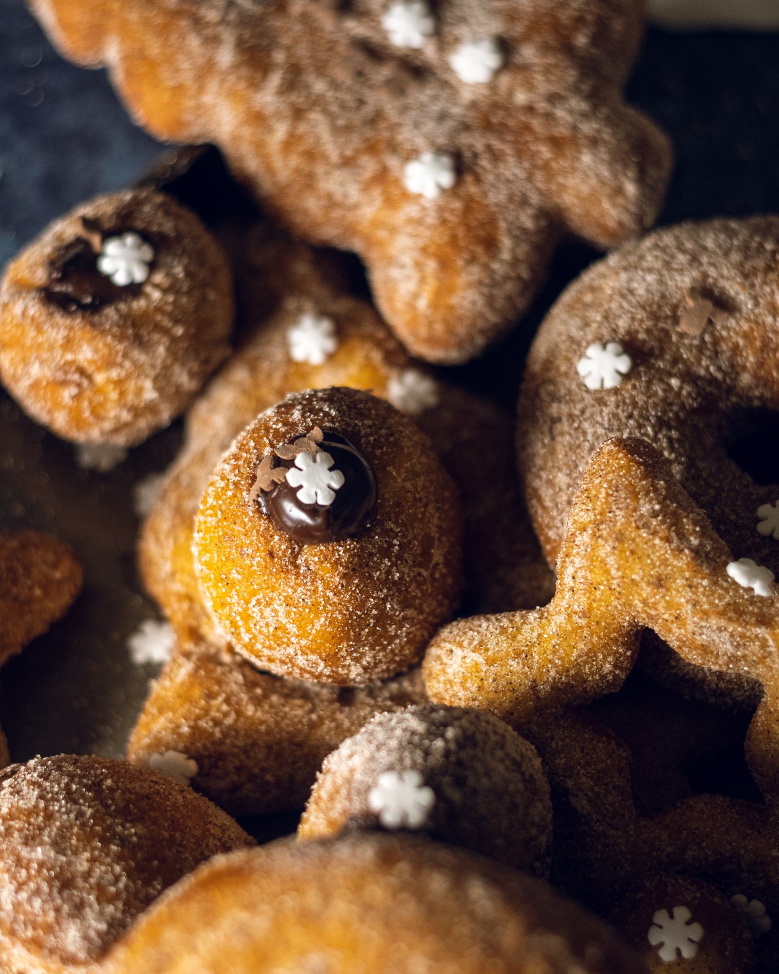 close up of a chocolate-filled mini donut coated with cinnamon sugar, sitting on top of a selection of vegan donuts.