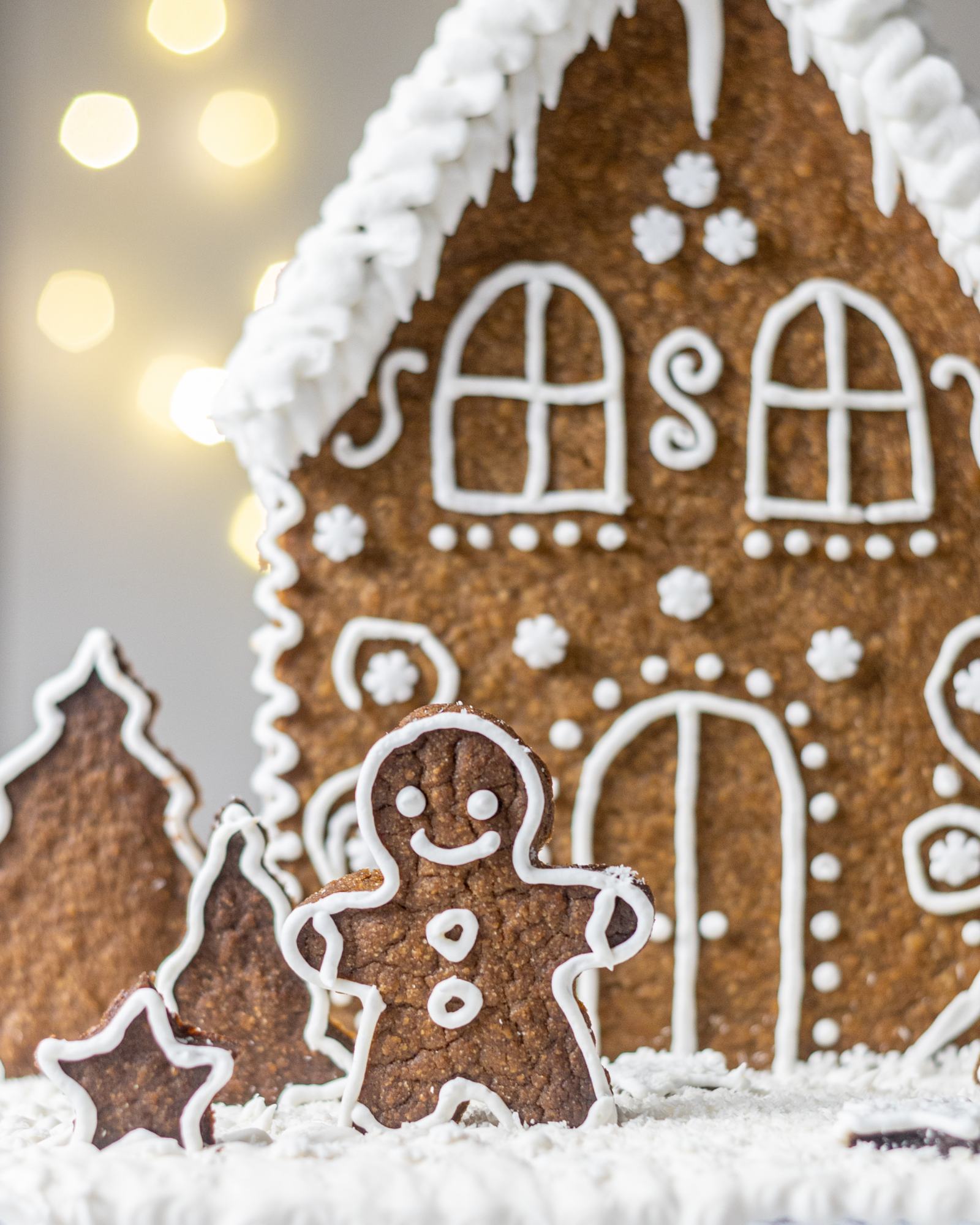 A little smiling gingerbread man standing in front of the house