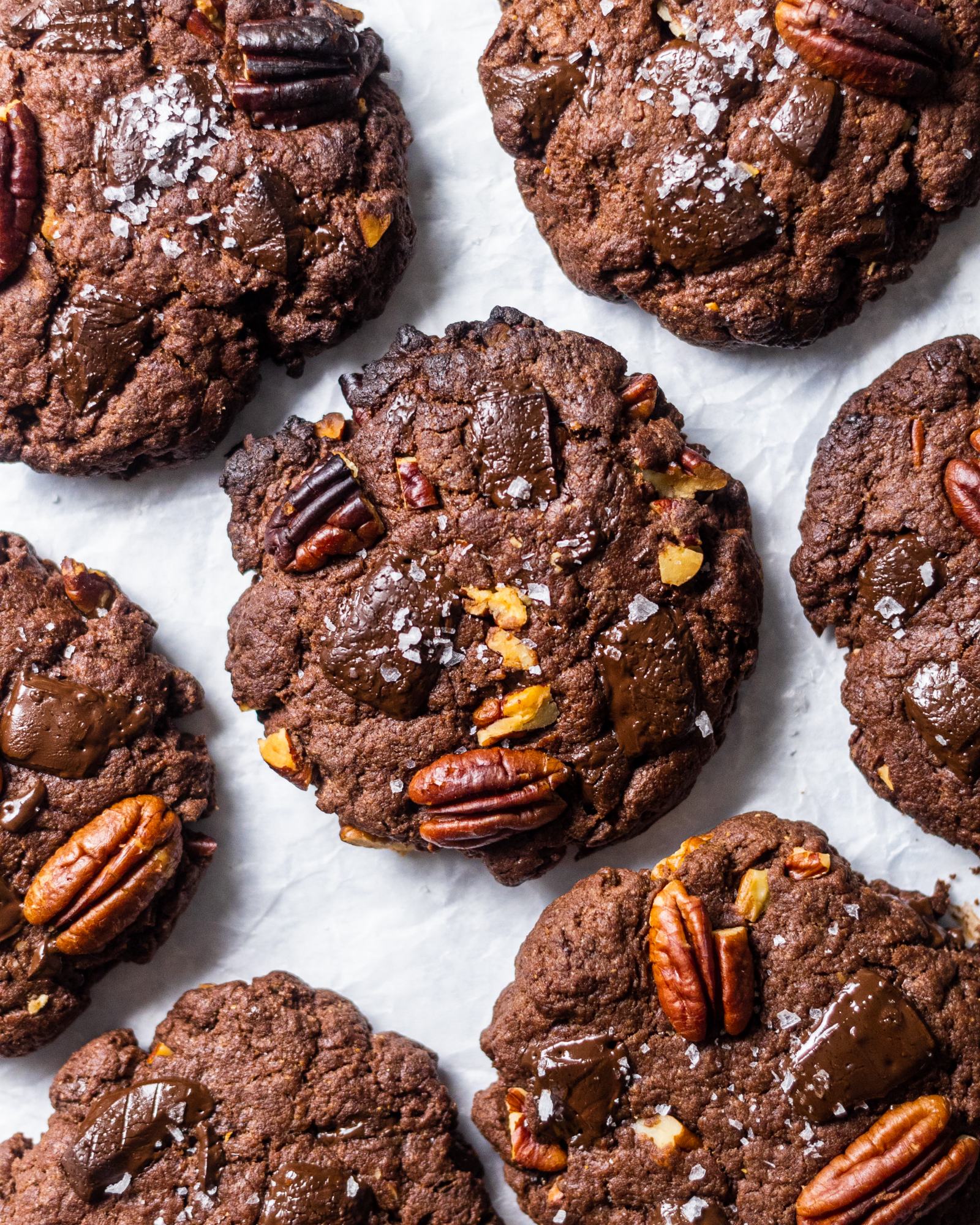 Vegan double Chocolate chip Cookies with pecans. photographed from above, arranged on white baking parchment